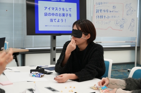 写真：アイマスクを付けた状態で、袋から取り出したお菓子の匂いを嗅ぐ参加者