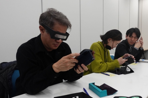 写真：弱視体験用メガネをかけ、スマホを見る参加者